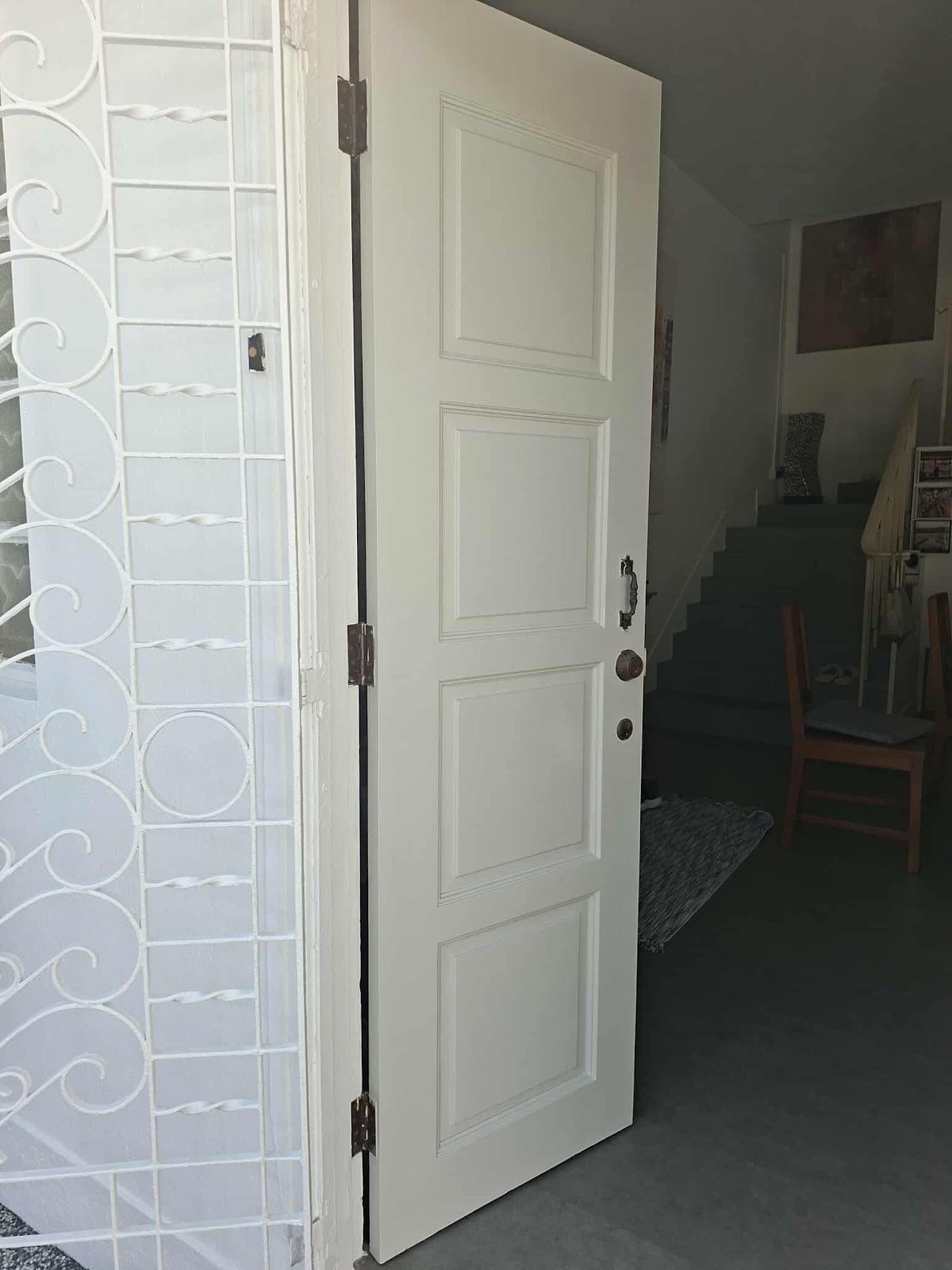 Freshly painted white four panel door and white wrought iron gate