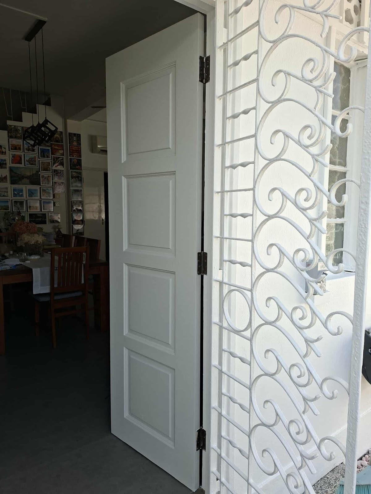 Freshly painted white door beside restored white gate scrollwork