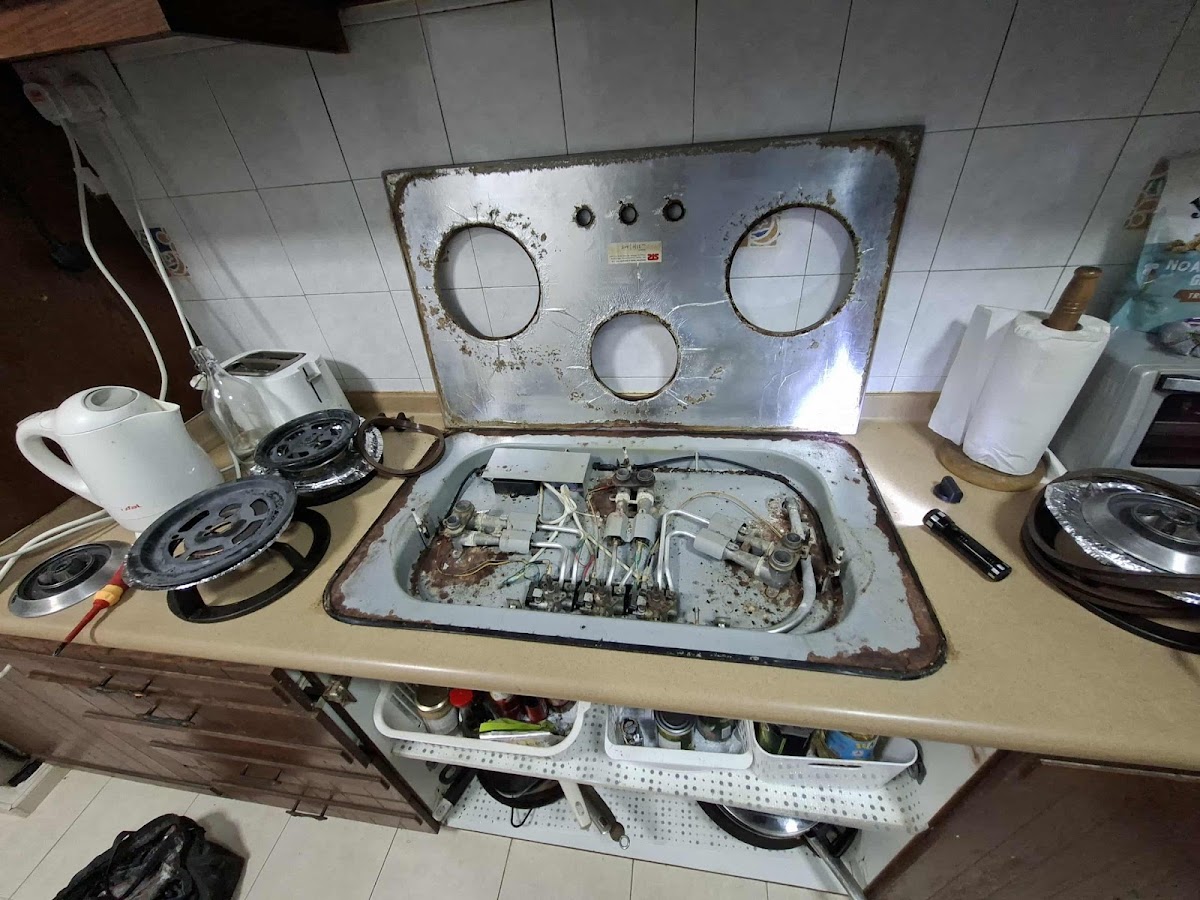 Built in gas hob lifted out mid repair with burners disassembled on the counter